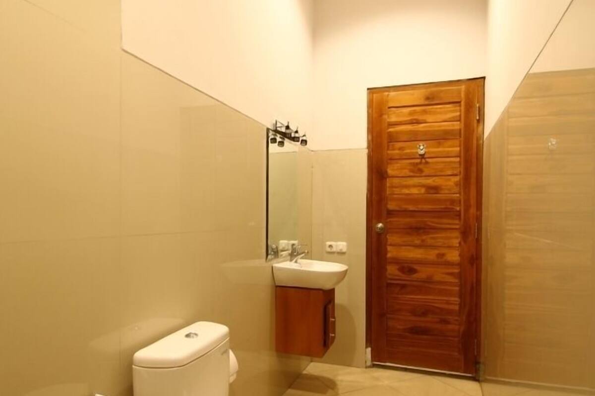 Une petite salle de bain moderne, équipée de toilettes, d’un lavabo et d’une porte en bois.