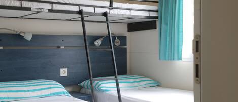 Dormitorio con literas, dos camas, una escalera y una ventana con cortinas.