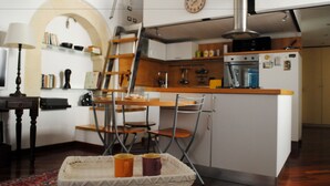 Una cocina compacta con una isla central, un área de comedor con sillas y una estantería.