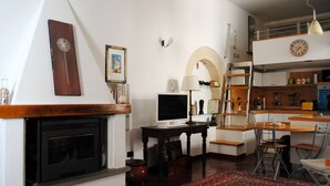 Una sala de estar con chimenea, televisión, comedor y cocina con entrepiso.