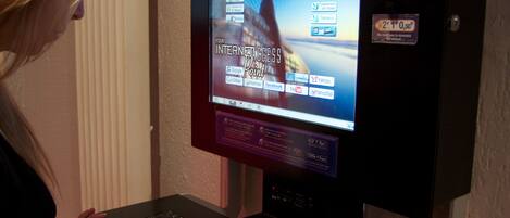A person using a laptop at a self-service kiosk with a screen displaying internet access options.
