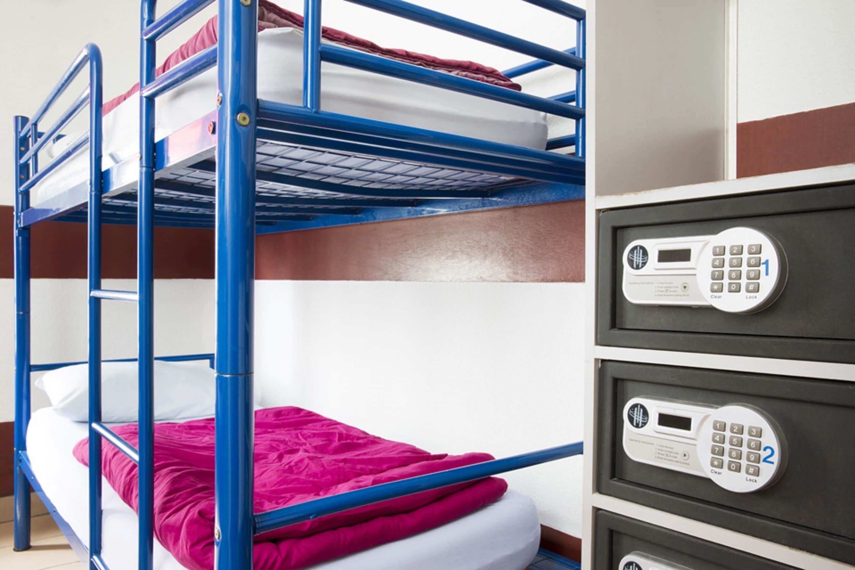 A bunk bed with a red blanket and a control panel with numbered buttons.