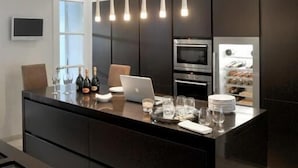 Una cocina moderna con una isla central, electrodomésticos integrados e iluminación colgante.