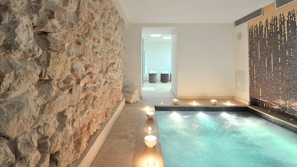 Un área de spa con pared de piedra, piscina y pared decorada con mosaicos.