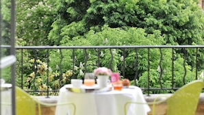Un balcón con una mesa lista para comer, rodeado de exuberante follaje verde.