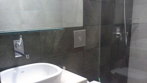 A bathroom with a white sink, a toilet, and a glass shower enclosure. - Apartment by the Sea - Sea Ezta by Otium (Colombo)