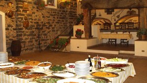 A buffet table with various dishes, a stone wall, and a rustic wooden ceiling. - Agriturismo Masseria Portiere Stella (Paterno)