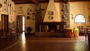A rustic interior with a stone fireplace, wooden beams, and a brick floor. - Agriturismo Masseria Portiere Stella (Paterno)
