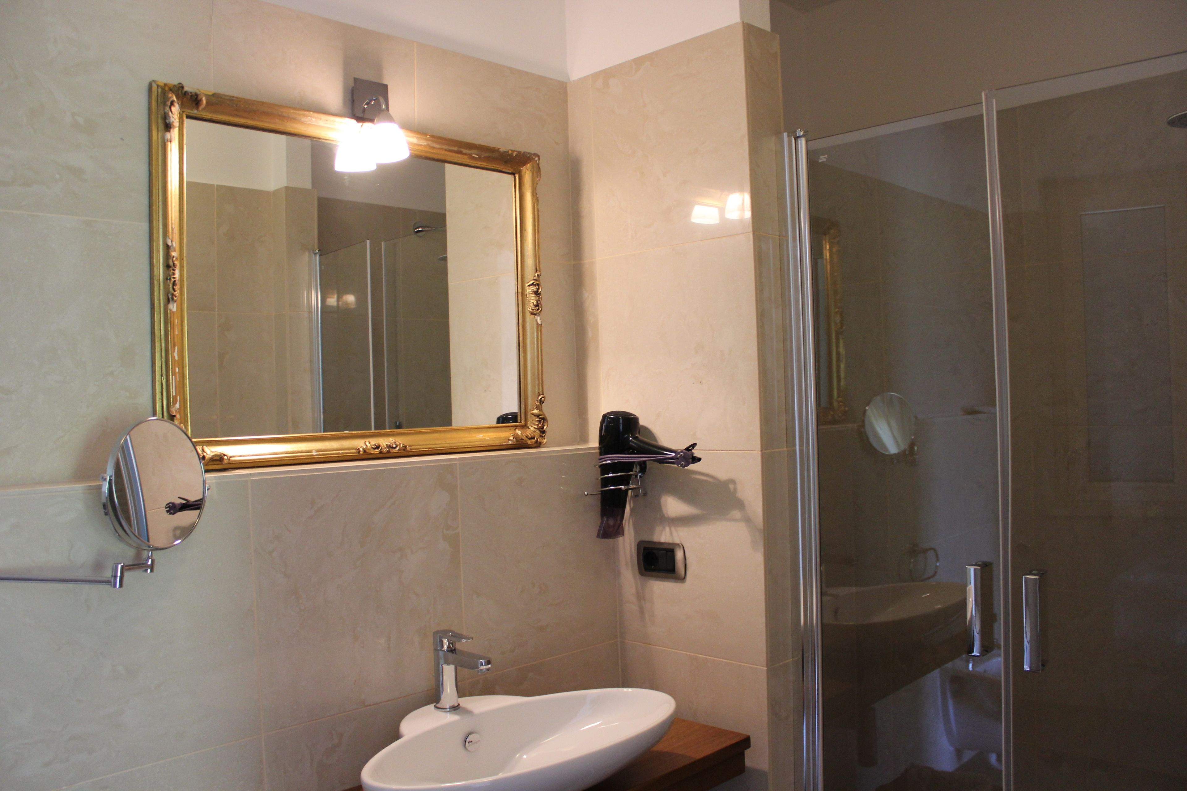 Un baño con un espejo grande, un lavabo y una zona de ducha.