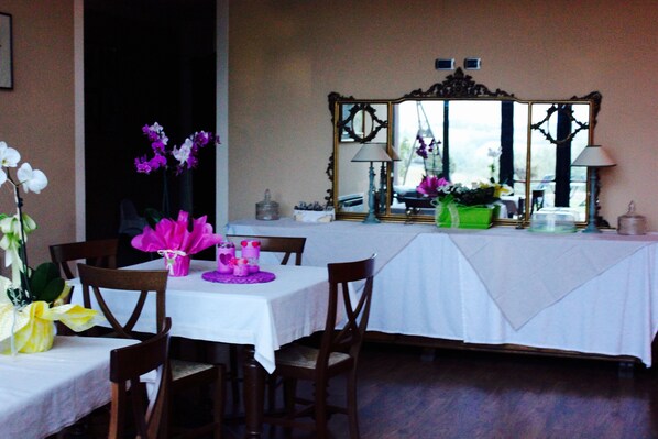 Comedor con mantel blanco, sillas de madera y un espejo decorativo.