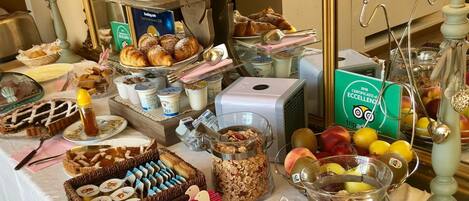 A buffet table with various food items including pastries, fruits, and condiments.