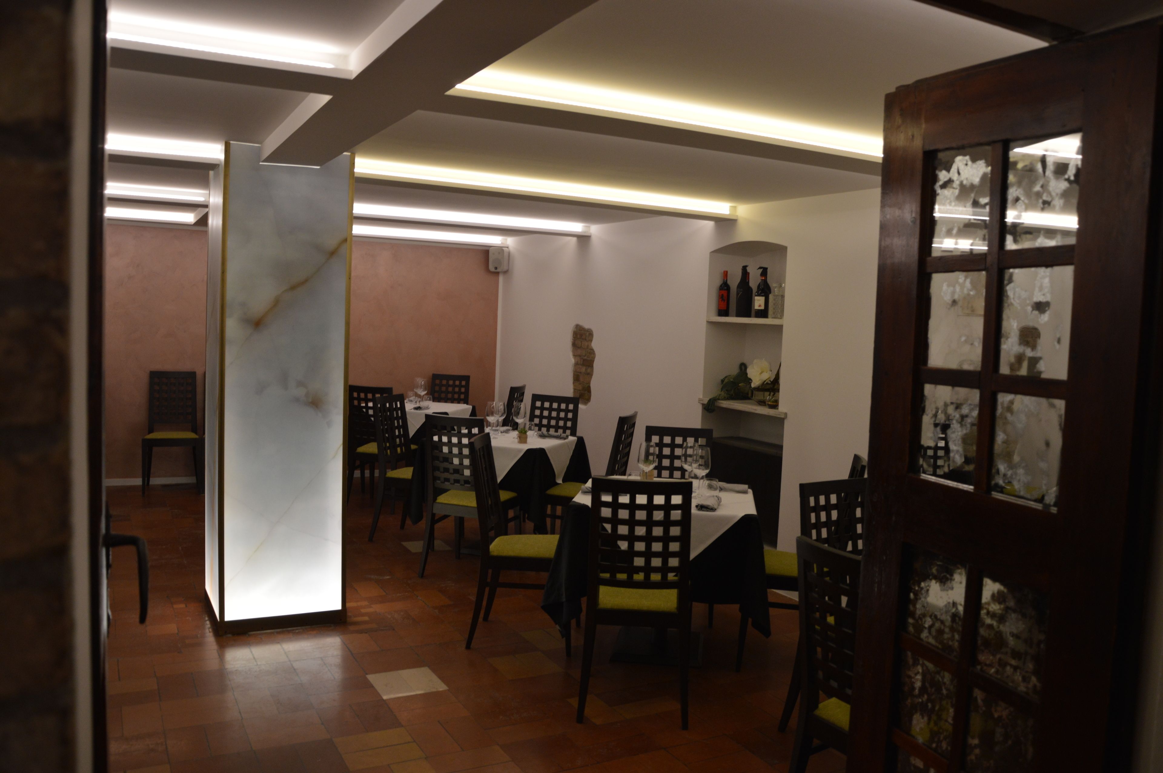 Un espace repas avec des tables et des chaises, une cloison en bois et un mur avec des étagères.
