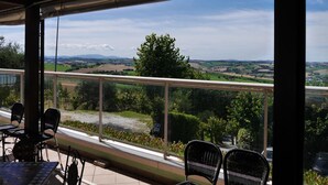 A covered outdoor seating area with a view of a rural landscape. - La Cantinella (Ostra)
