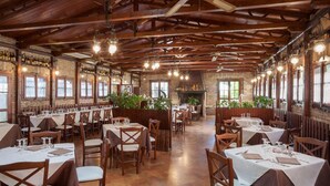 A restaurant with wooden beams, brick walls, and tables set for dining. - La Cantinella (Ostra)