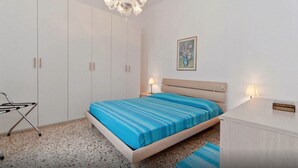Une chambre à coucher comprenant un lit, des lampes de chevet, une table de chevet, une armoire et un lustre.