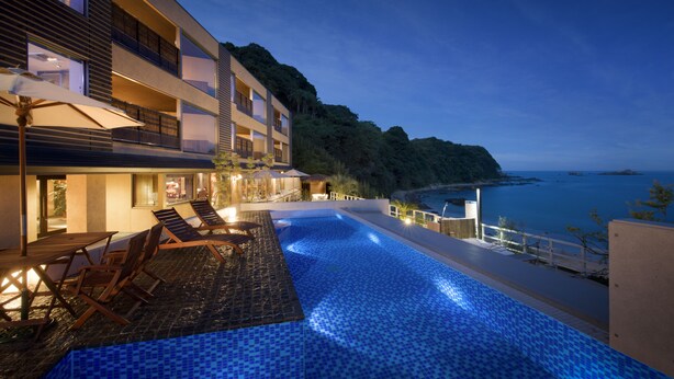 Un hôtel moderne doté d’une piscine, d’un espace extérieur aménagé et offrant une vue sur la mer.