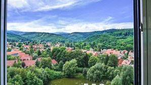 A view of a town with red-roofed houses surrounded by lush greenery and hills in the background. - Hasseröder Burghotel (Wernigerode)