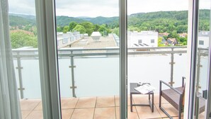 A balcony with a view of a river and a hilly landscape.