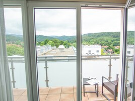 A balcony with a view of a river and a hilly landscape.