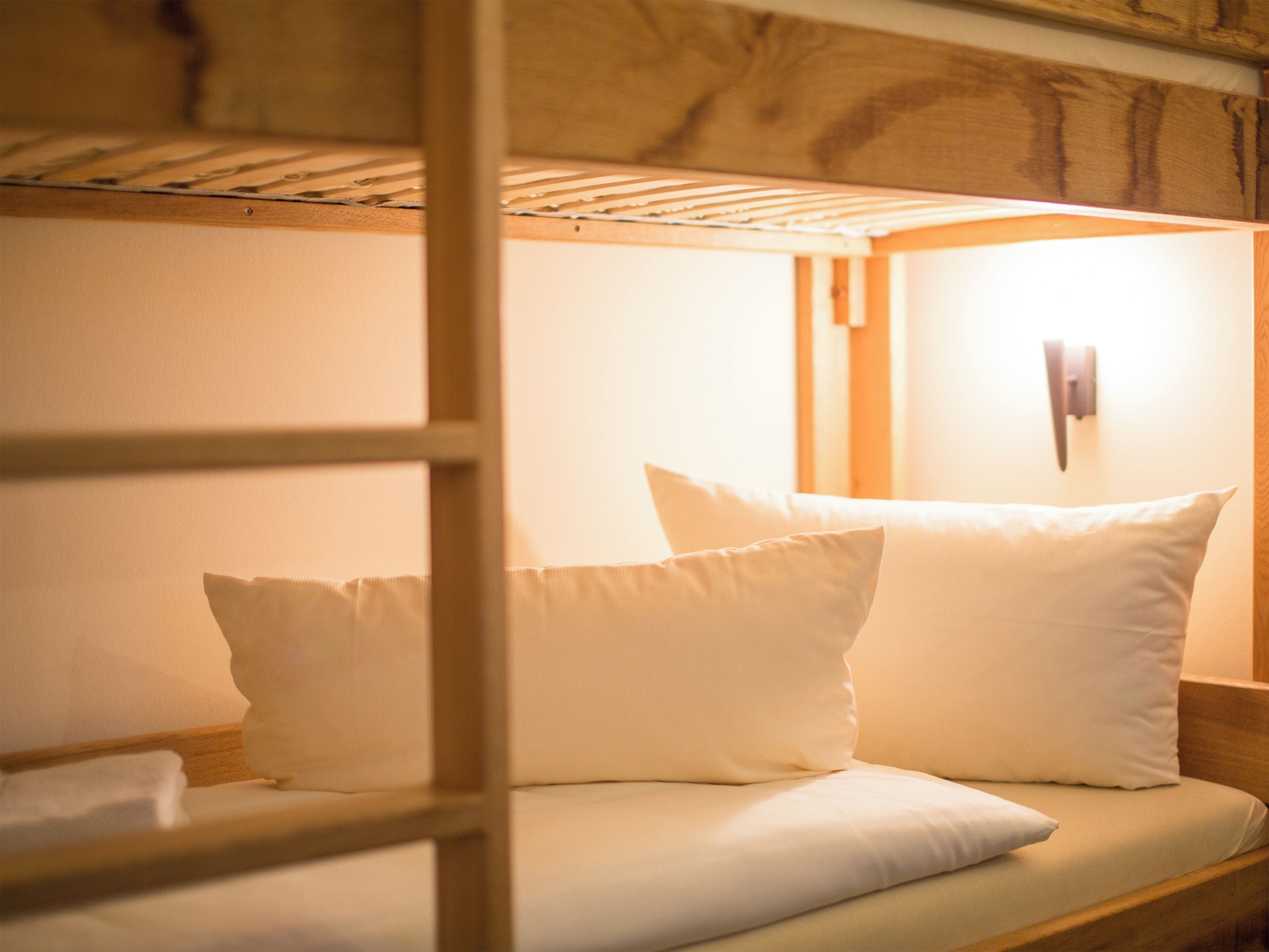 A bunk bed with white bedding and a wooden headboard.