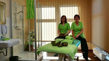 Enjoy a rejuvenating spa experience with a glass shower, sink, and massage table.