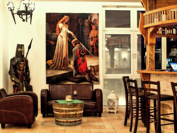 A room with a wooden barrel coffee table, leather sofas, a wooden bar with stools, and a large historical painting on the wall. - Hasseröder Burghotel (Wernigerode)