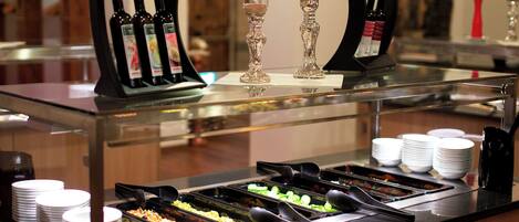 A buffet area with various food options, a wine cooler, and a selection of glasses.
