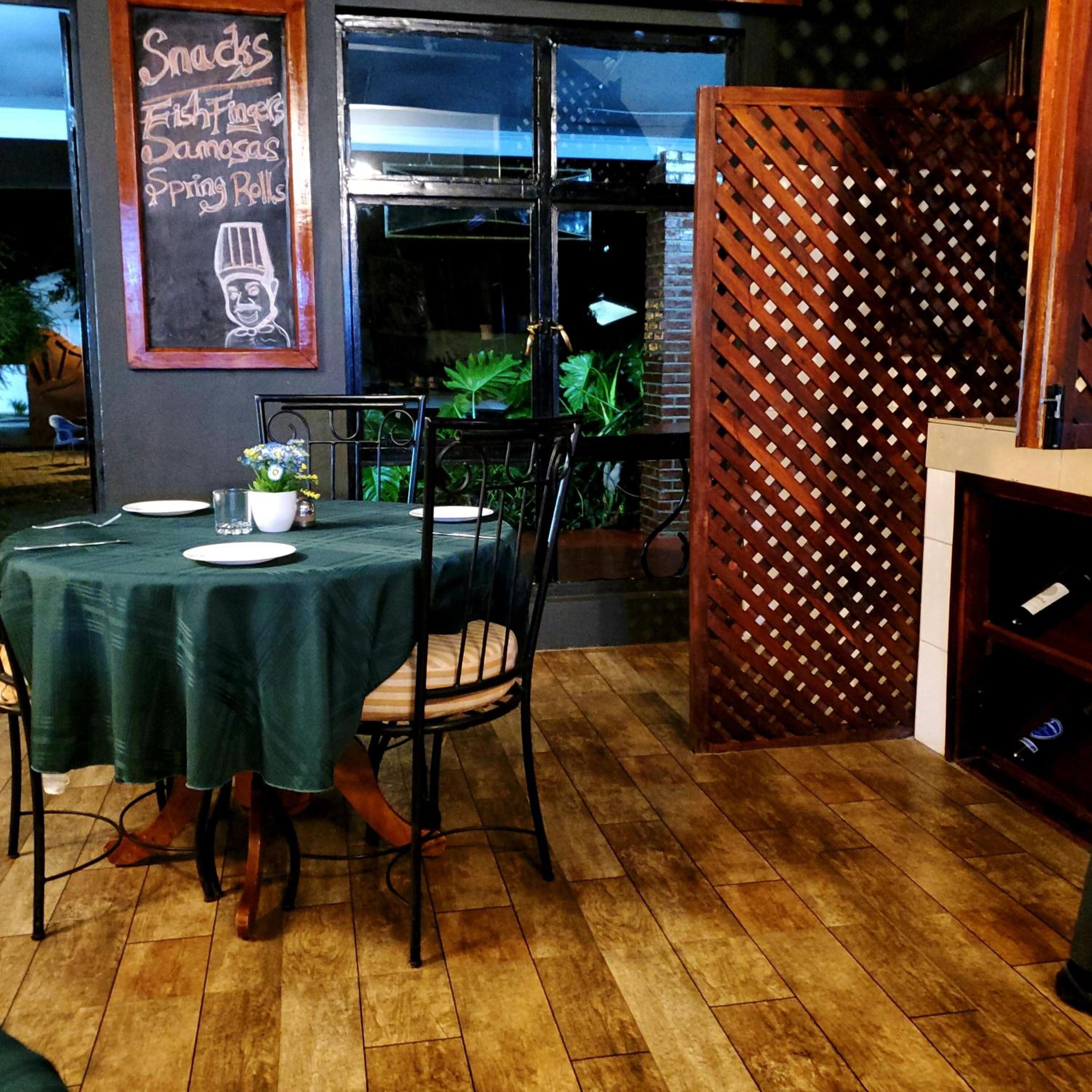 A restaurant interior with a table set for two, a chalkboard menu, and a wooden lattice partition.