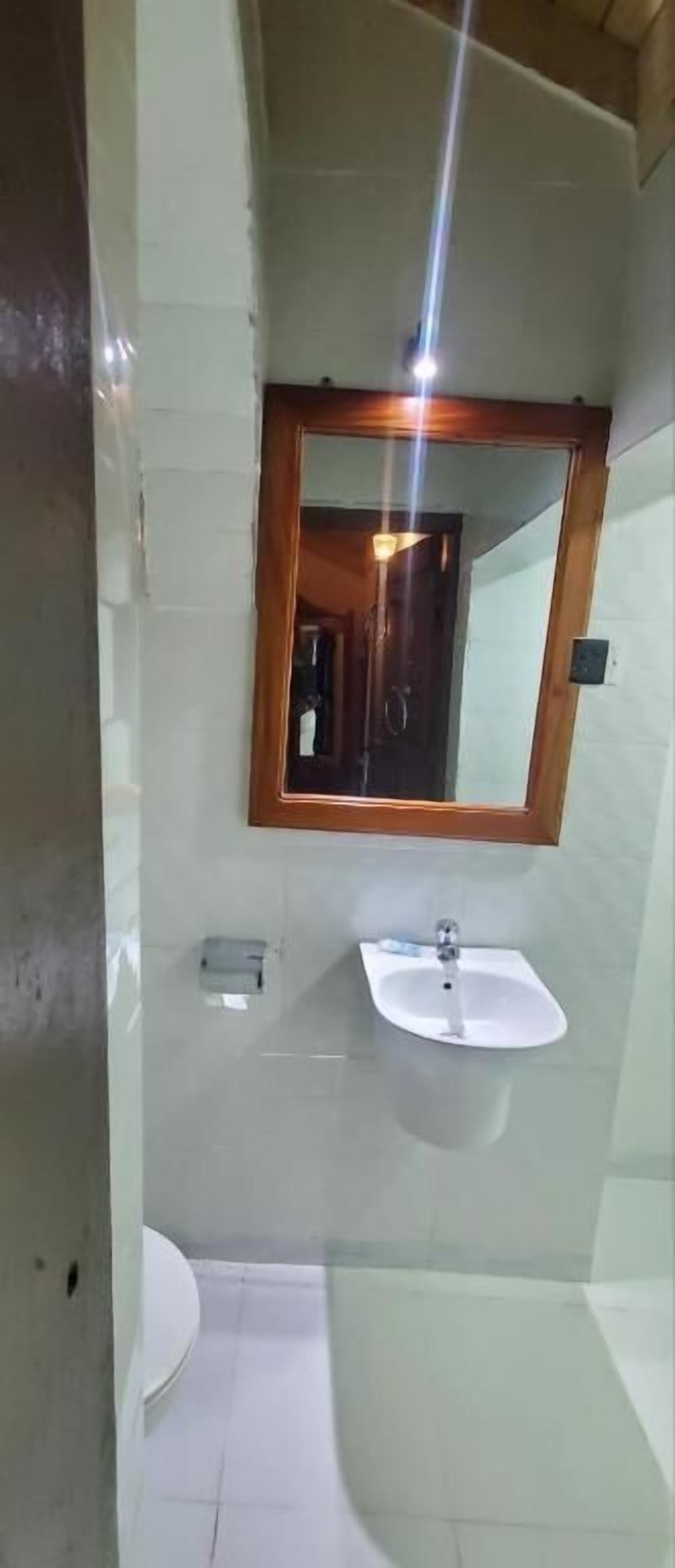 Un bagno con un lavandino bianco, uno specchio e un water.