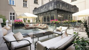 A spacious outdoor seating area with modern furniture and a glass enclosure.