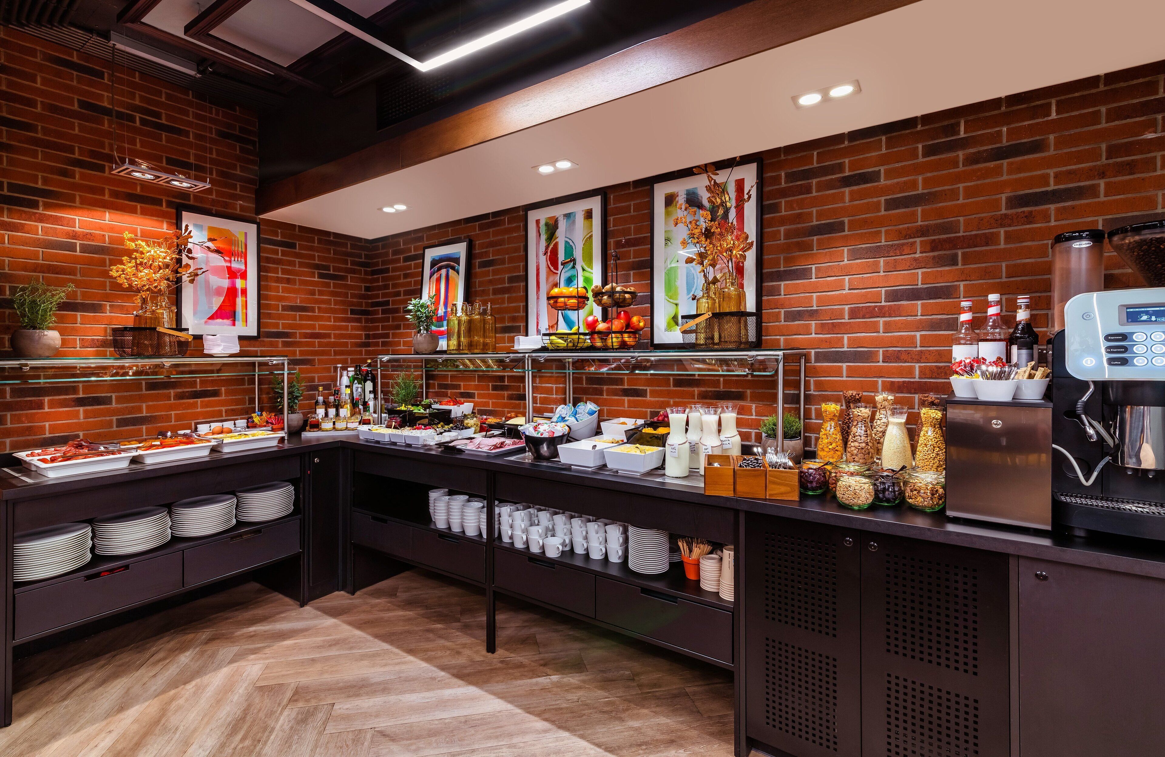 Un espace buffet avec un mur en briques, divers plats et une machine à café.