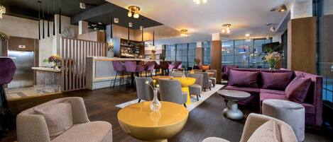 A modern lounge area with seating, a bar, and a staircase.
