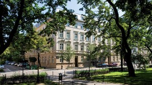 A multi-story building with a classic architectural style, surrounded by lush greenery and a well-maintained lawn.