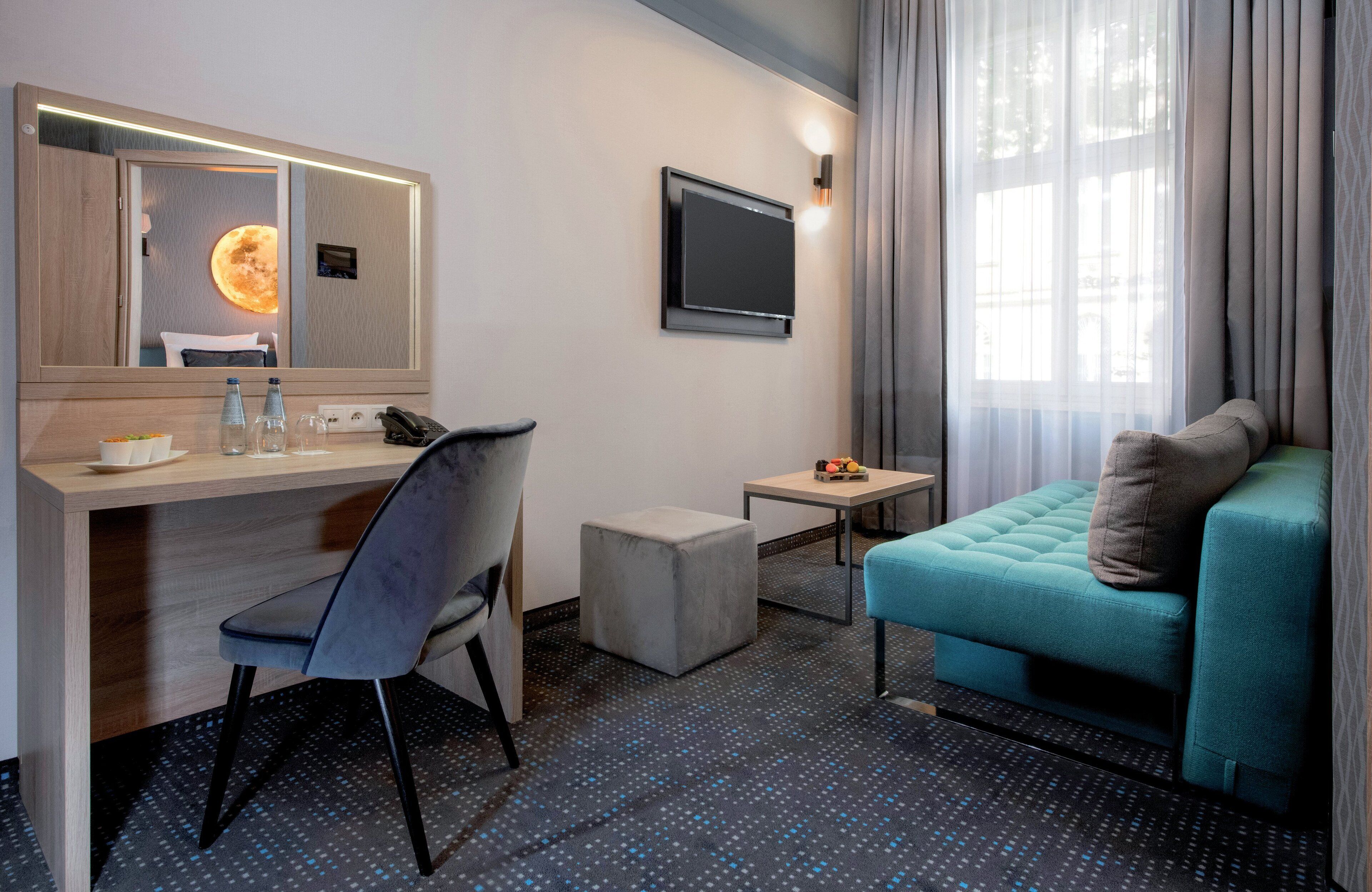 Une chambre d’hôtel équipée d’un bureau, d’une chaise, d’une petite table et d’un canapé.