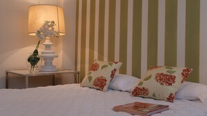 A neatly made bed with floral pillows, a bedside table with a lamp, and a book on the bed. - Casa delle Ortensie (Venice)
