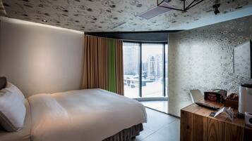 Habitación de hotel moderna con una cama grande, un escritorio de madera y vistas a la ciudad a través de la ventana.