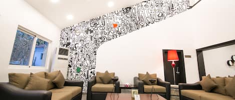 Una sala de estar moderna con dos sofás, una mesa de centro y una lámpara de pie roja. Un mural abstracto blanco y negro único decora la pared.