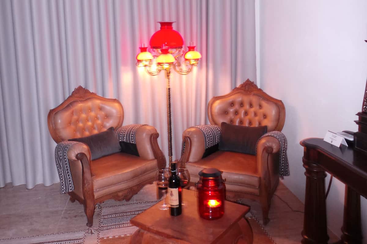 A living room with two leather armchairs, a wooden coffee table, a red floor lamp, and a television on a stand.