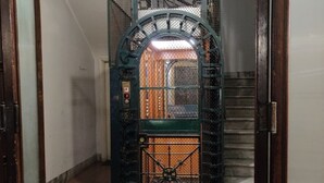 A hallway with a metal gate leading to a staircase. - Corso Experience (Rome)