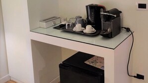A compact kitchenette with a coffee machine, cups, and a small trash bin. - Corso Experience (Rome)
