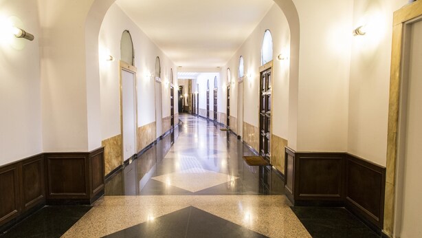 A long, well-lit hallway with arched ceilings and a polished floor. - Corso Experience (Rome)