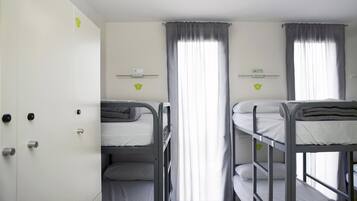 Un dormitorio con literas, un armario y una ventana con cortinas.
