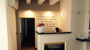 Una recepción con un letrero en la pared en italiano, una barra negra y un cartel que dice "Palazzo Sisto".