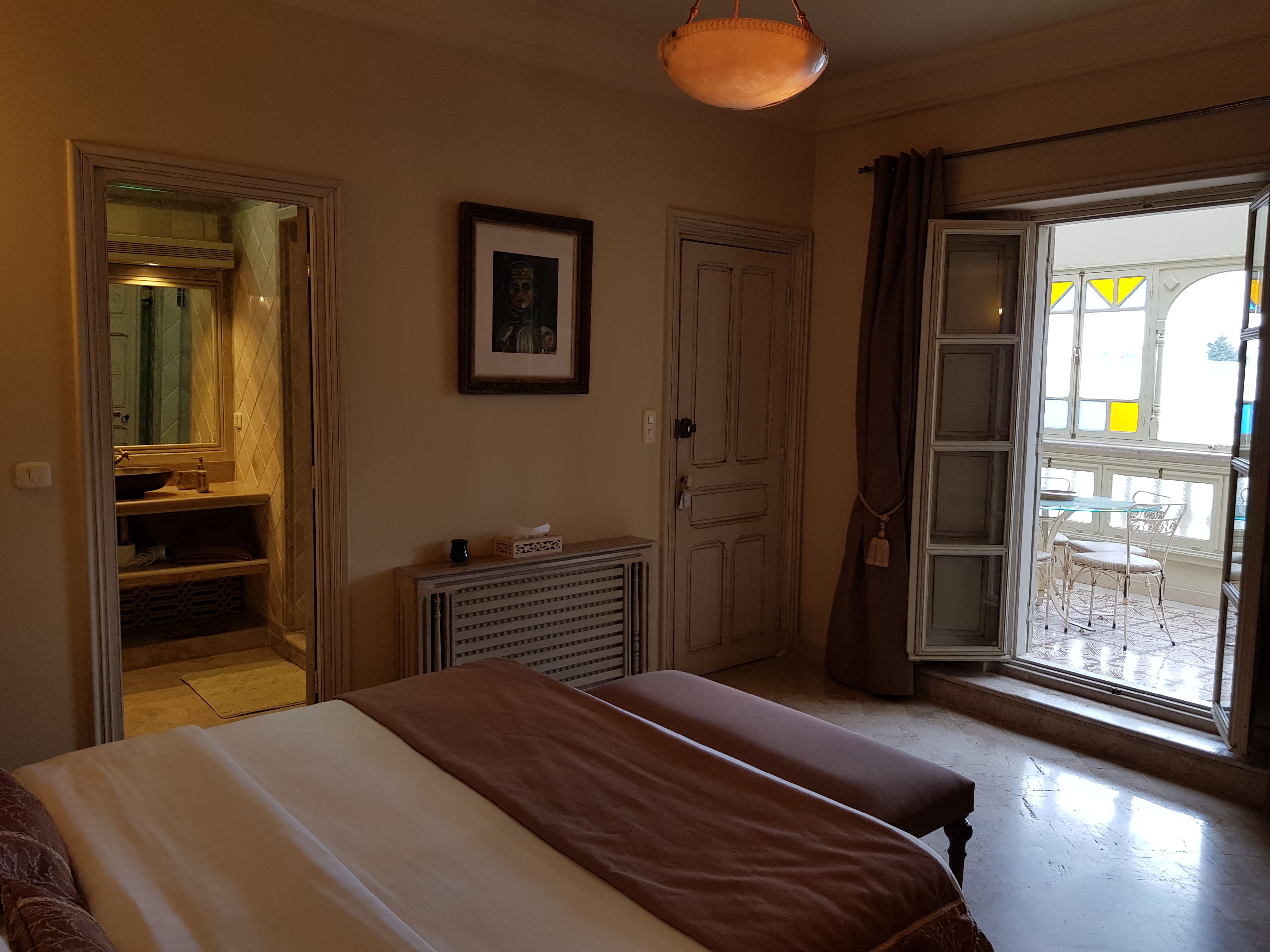A bedroom with two beds, a bathroom, and a dining area with a view.