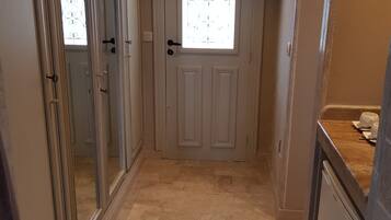 A hallway with a white door, a window with decorative iron bars, and a tiled floor.