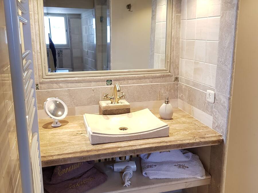 Un baño con un lavabo color beige, un espejo y una ducha a la vista al fondo.