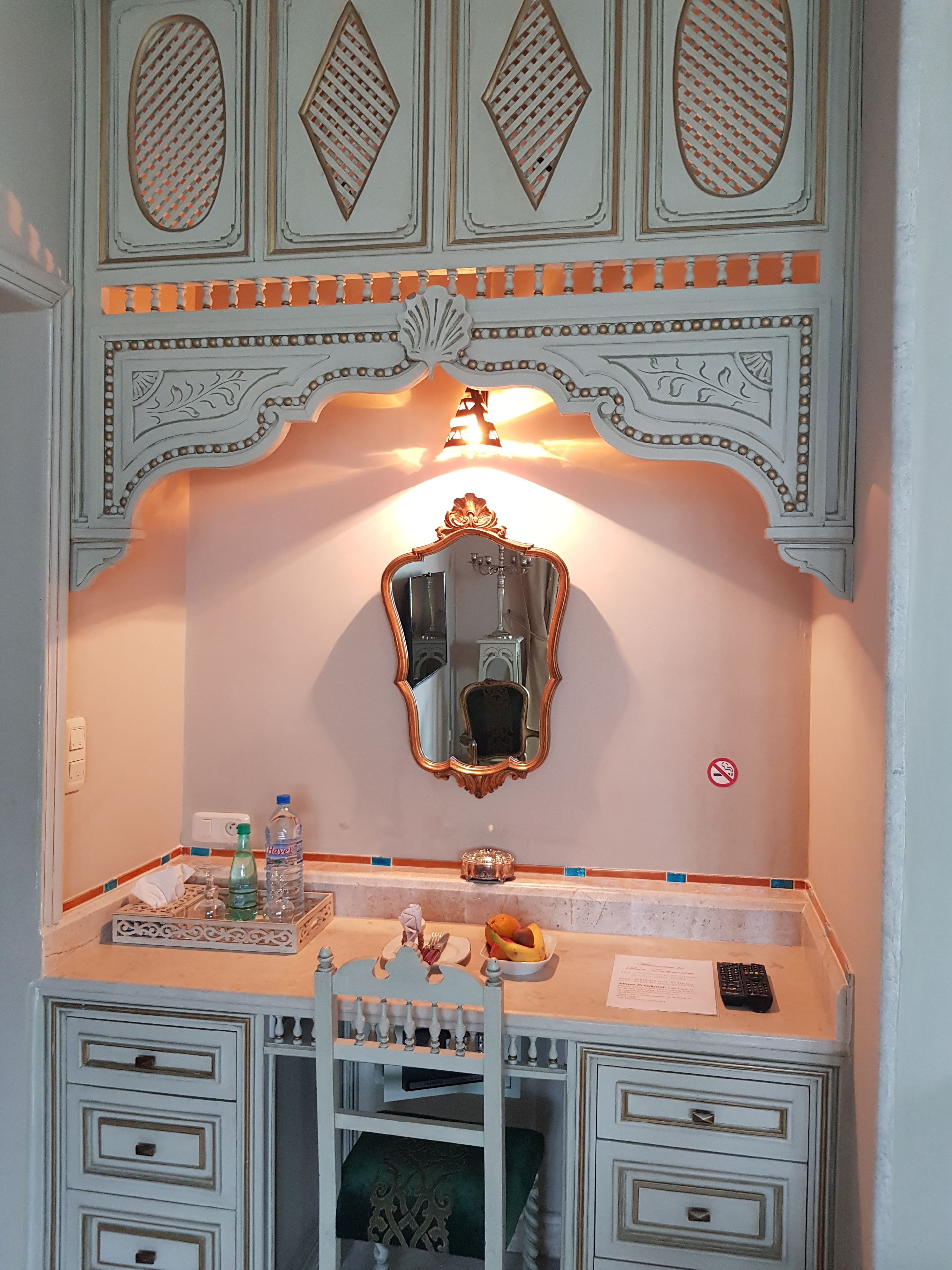 Une pièce comprenant un bureau, un miroir et un plafond décoratif.