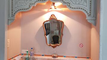 Une pièce comprenant un bureau, un miroir et un plafond décoratif.