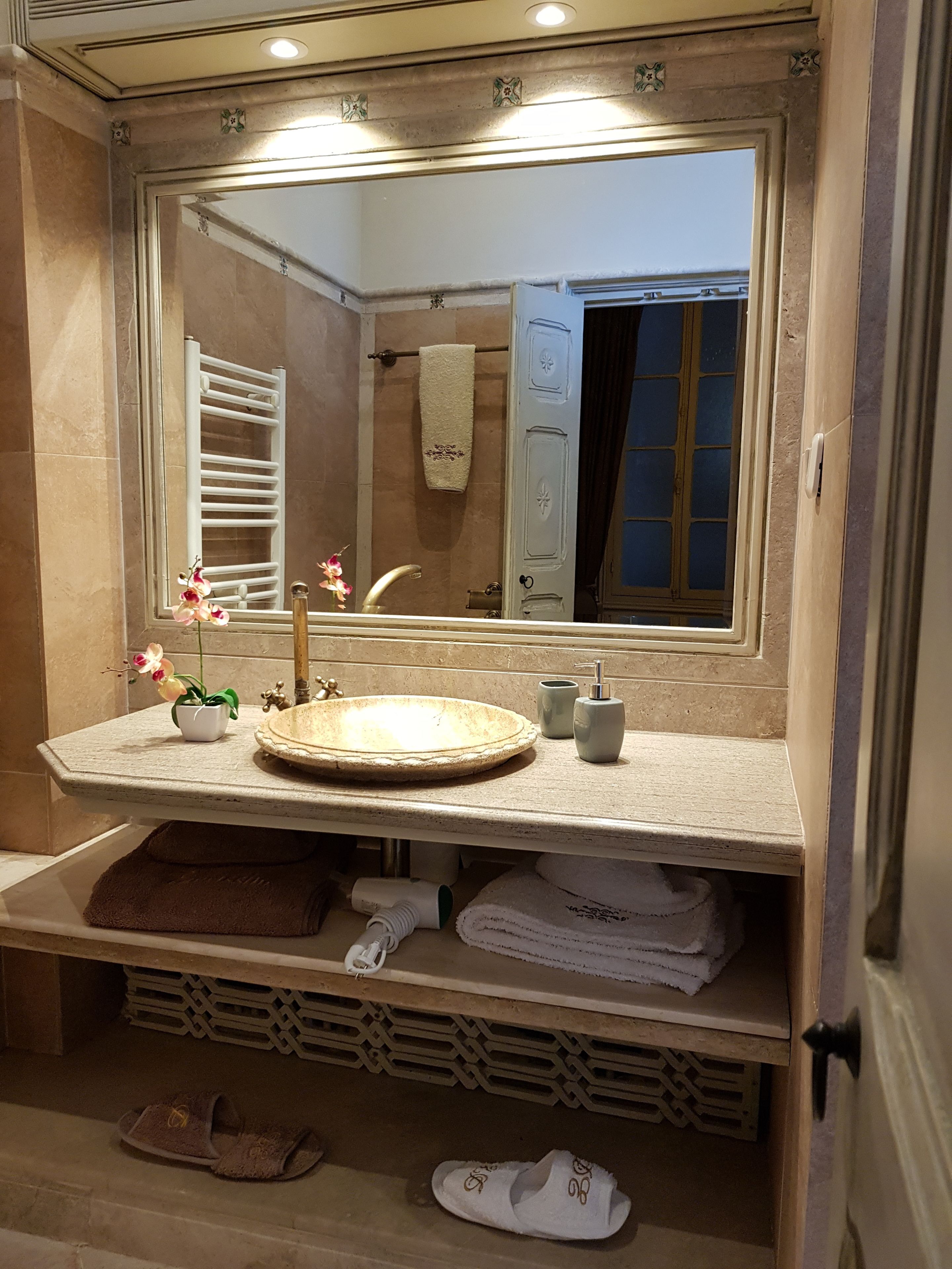 Un baño con un lavabo redondo, un espejo, un perchero para toallas y un estante para toallas.