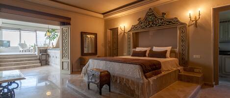 A spacious bedroom with a large bed, a small stool, and a view of the outside.